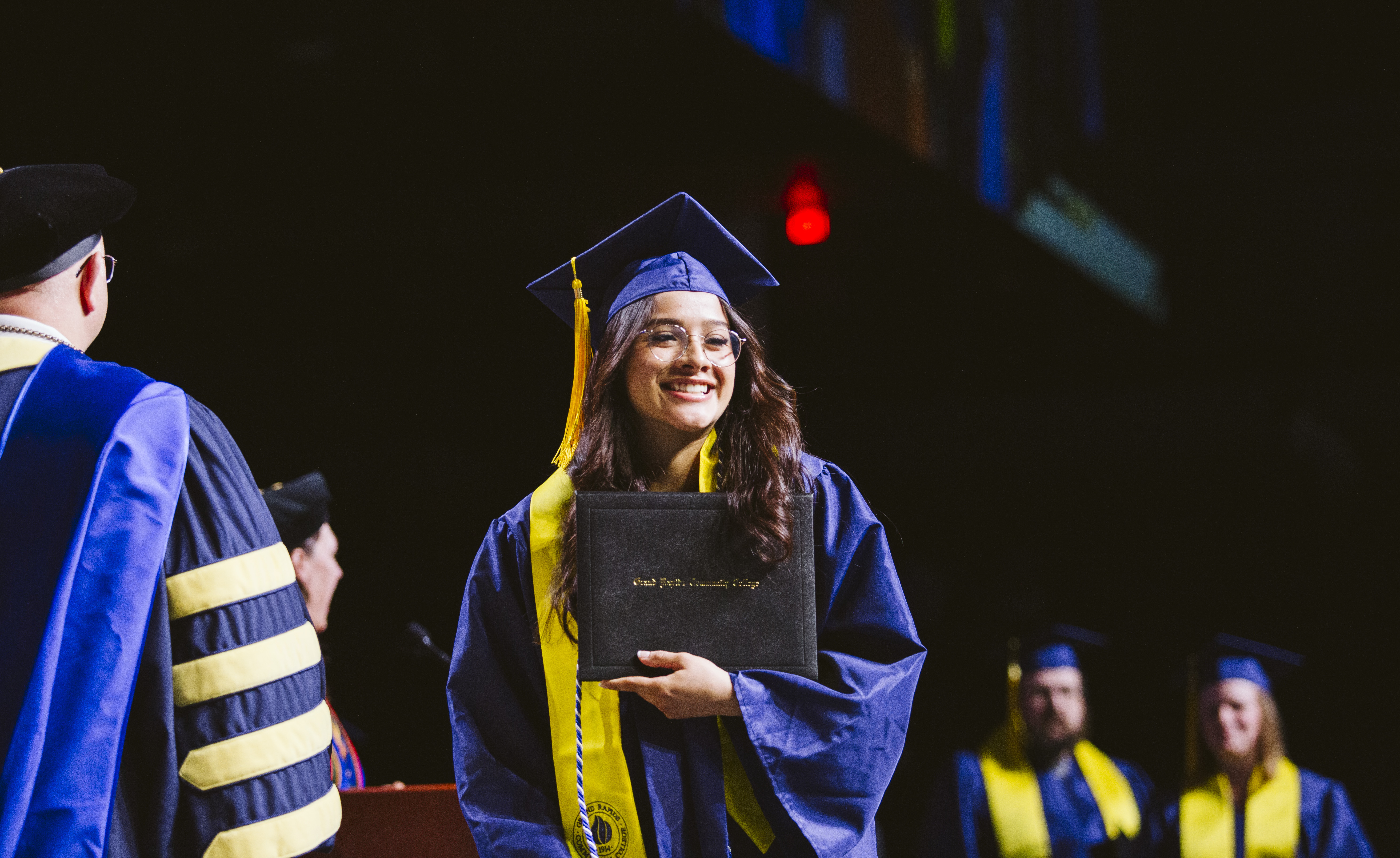 GRCC Graduate holding diploma at Commencement in 2024